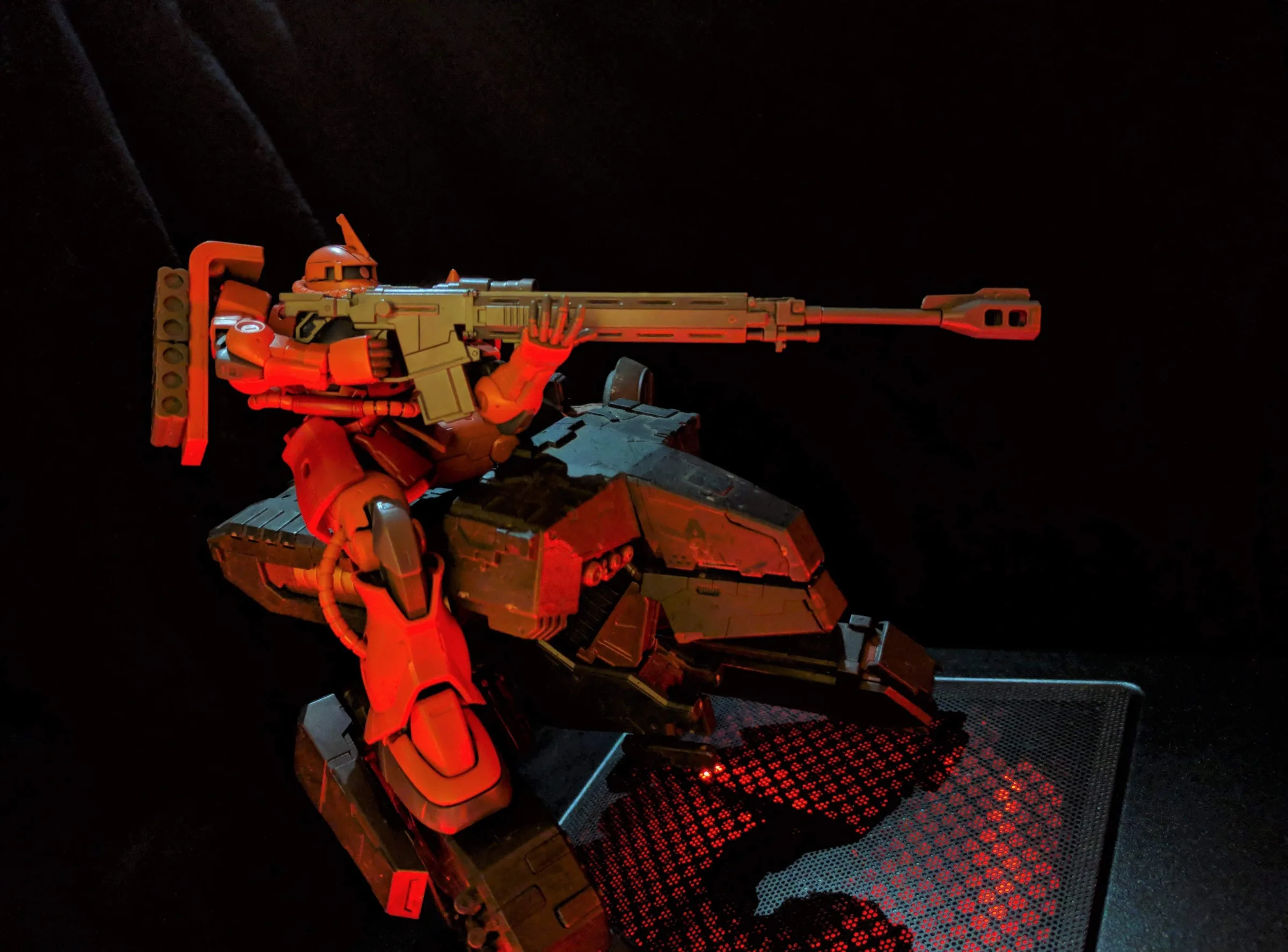 Char's Zaku II (The ORIGIN ver.) aiming a long sniper rifle from a dark mobile armor base lit in red, standing on top of Metal Gear REX